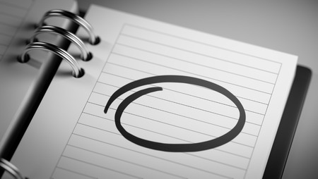 Closeup of a personal agenda setting an important date representing a time schedule. Circle mark written on a white notebook to remind you an important appointment.の写真素材