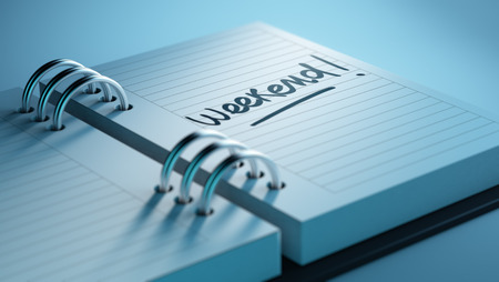 Closeup of a personal agenda setting an important date representing a time schedule. The words Weekend written on a white notebook to remind you an important appointment.の写真素材