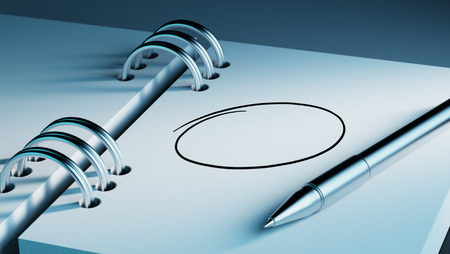 Closeup of a personal agenda setting an important date writing with pen. Circle mark written on a white notebook to remind you an important appointment.の写真素材