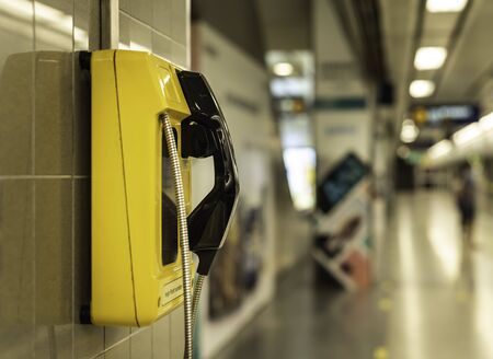 public yellow telephone attached on wall inside the building for customer who need  make a call to othersの写真素材