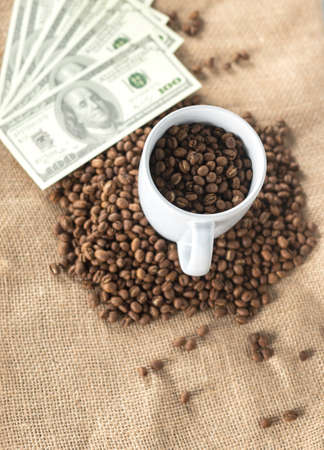 coffee beans on a coffee cup put on heap of coffee beans and dollar banknote from top view. concept for coffee trading. coffee beans economy.の写真素材