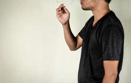 man holds a cigarette for smoking behind the wall. concept for narcotic,illness.の写真素材