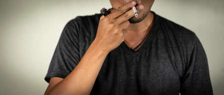man holds a burning cigarette on lip during smoking. concept for illness, drug, cancer.の写真素材