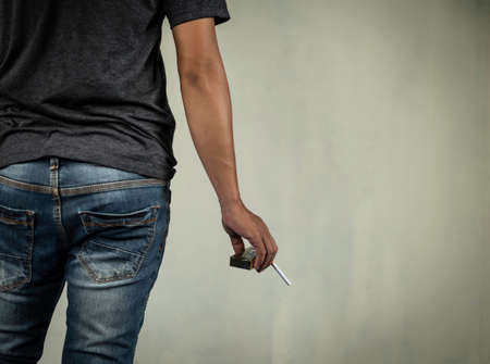 man holds cigarette looking from back concept for crime, illness, cancer, narcotic.の写真素材