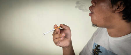 man release smoke out of mouth during smoking behind the wall. concept for narcotic, illness, crime.の写真素材