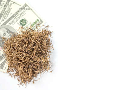 banknote lay under heap of tobacco on white background from overhead view with copy space. concept for tobacco trading.の写真素材