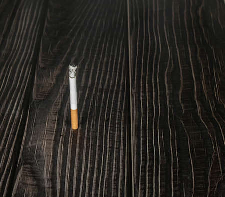 a burning cigarette on a wooden table. narcotic concept.の写真素材