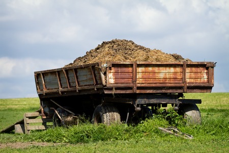 Tow tractor with horse manure standing on pastureの写真素材