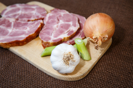 Close up of a cutting board with smoked pork and garlicの写真素材