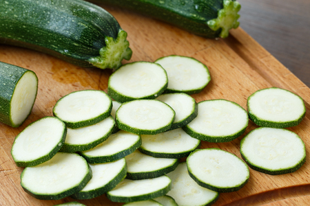 Fresh sliced zucchini on cutting board, on wooden backgroundの写真素材
