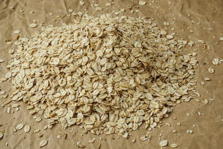 Pouring oatmeal flakes on crumpled paper backgroundの写真素材