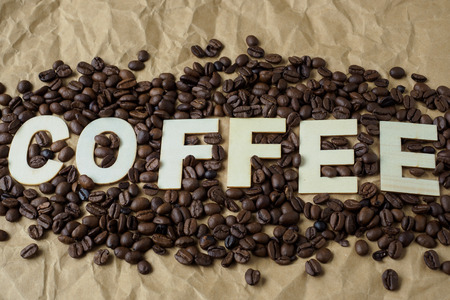Roasted coffee beans on brown wrapping paper. The word "coffee"の写真素材