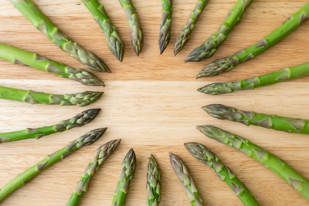Raw garden asparagus stems. Fresh green spring vegetables on wooden background. (Asparagus officinalis).の写真素材