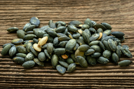 Pumpkin seeds seasoned using sea salt. Pumpkin seeds over wooden table.の写真素材