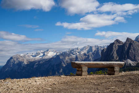 Wooden bench and in the background view of the mountain peaks. Belluno Province, Dolomiti Alps, Italyの写真素材