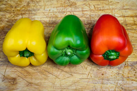 Peppers in three colors on a kitchen breadboard. Preparing vegetables for a healthy salad.