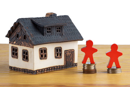House with stacks of money and a figure model symbolizing rising real estate prices.の写真素材