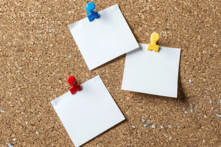 Three blank white notes attached with colorful push pins to a corkboard, space for custom textの素材