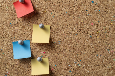 Blank pinned notes attached with colorful push pins to a corkboard, space for custom textの素材