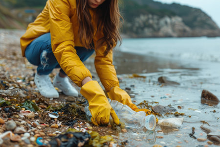 A female volunteer is collecting plastic garbage on the seashore. Cleaning of the coastal zone.の素材