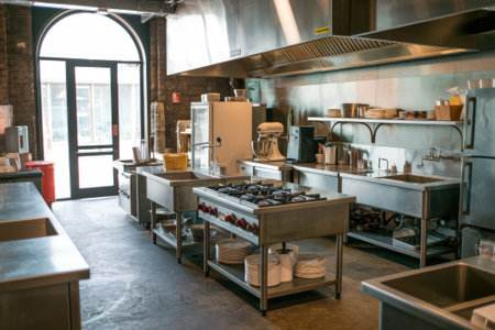 Spotless industrial kitchen featuring stainless steel appliances, counters, and sinks, indicating a professional culinary environmentの素材