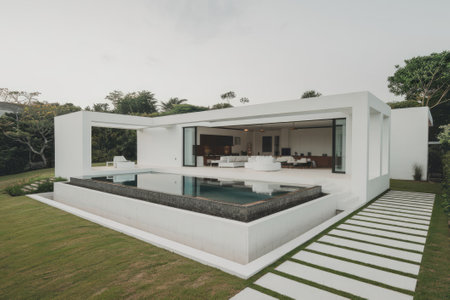 Luxurious white villa with infinity pool, surrounded by a perfectly manicured lawn and tropical vegetation, offering a tranquil and relaxing atmosphereの素材