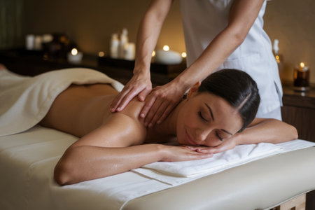 Professional masseuse giving a relaxing back massage to a client lying on a massage table in a spaの素材