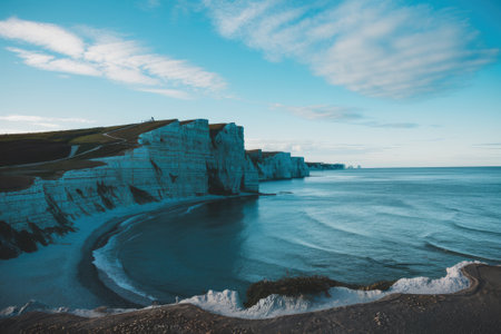 The white chalk cliffs of the seven sisters on the Sussex coast of England meet the blue waters of the English channel, creating a breathtaking coastal landscape at sunsetの素材