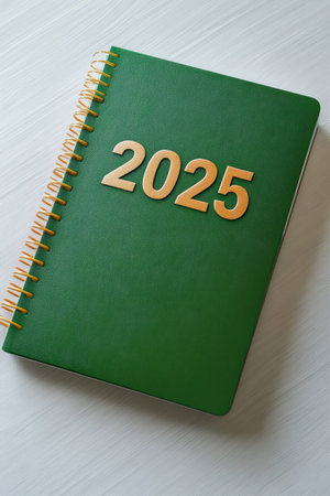 Green notebook displaying the year 2025 in gold lettering, symbolizing future planning and organization for upcoming eventsの素材