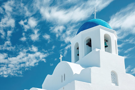Whitewashed church with iconic blue domes standing tall against the backdrop of Santorini's caldera and a vibrant blue skyの素材