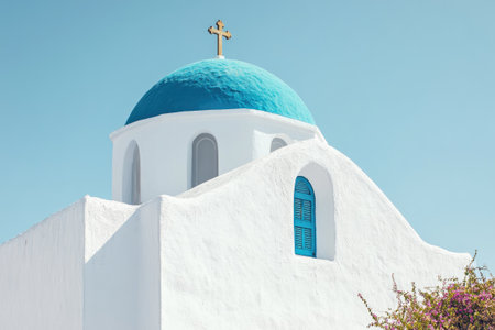 Whitewashed church with iconic blue domes standing tall against the backdrop of Santorini's caldera and a vibrant blue skyの素材