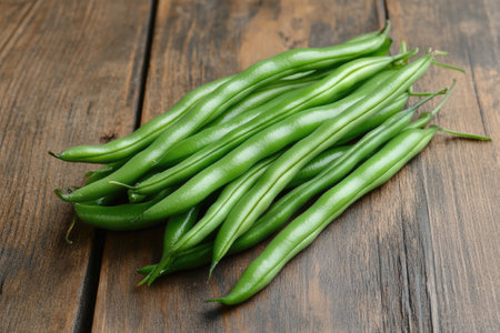 Freshly picked green beans create a vibrant display on a rustic wooden table, showcasing their natural beauty and garden-fresh appealの素材