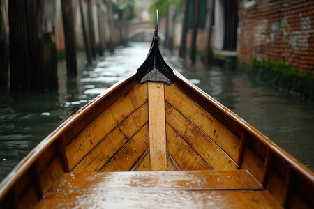 Close-up of wooden boat navigating a narrow canal in Venice, Italy, during a rainy dayの素材