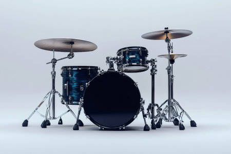 Blue and black drum set standing alone in a white room, ready for a drummer to start playingの素材