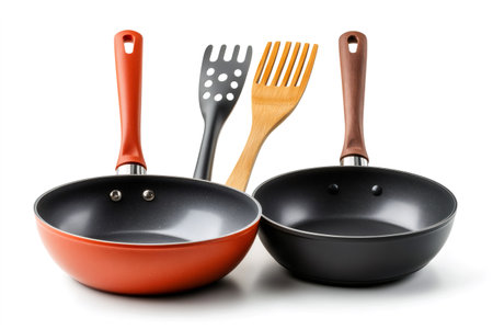 Two empty non-stick frying pans with kitchen utensils on a white background, ready for cookingの素材
