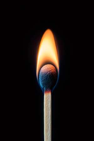 Single wooden match burning with bright flame on a dark background, creating a dramatic and captivating sceneの素材