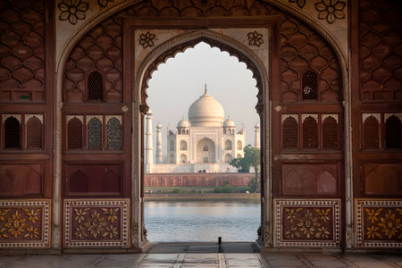 Ornate Mughal arch framing the Taj Mahal and its reflection in the Yamuna river in Agra, Indiaの素材
