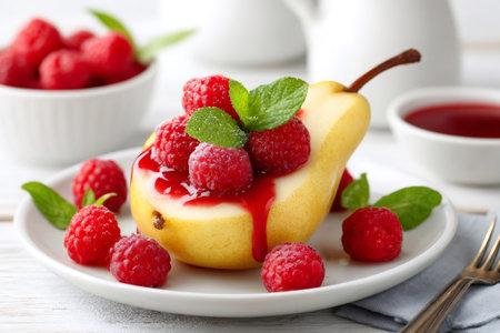 Yellow pear with raspberries and mint leaves covered with raspberry sauce creating an elegant and gourmet dessertの素材
