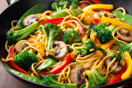 Noodles are stir fried with broccoli florets, sliced mushrooms, and colorful bell peppers in a wokの素材
