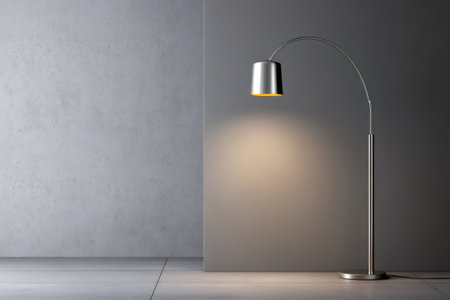 Modern metallic floor lamp illuminating a minimalist interior with concrete and gray walls, creating a cozy atmosphereの素材