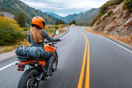Woman riding motorcycle on scenic mountain highway enjoying the freedom of open roadの素材