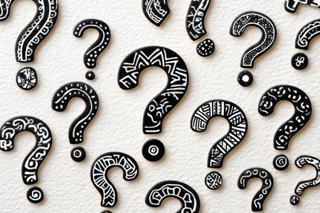 Question marks with different white tribal patterns are covering a black textured surface, creating a concept about questions and answersの素材