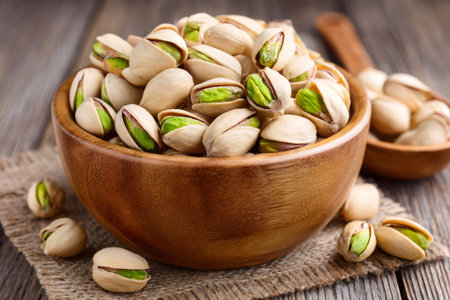 Pistachios in wooden bowl on rustic wooden table represent healthy snackingの素材