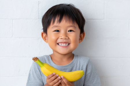 Happy boy showing a banana, promoting healthy eating habits for growing childrenの素材