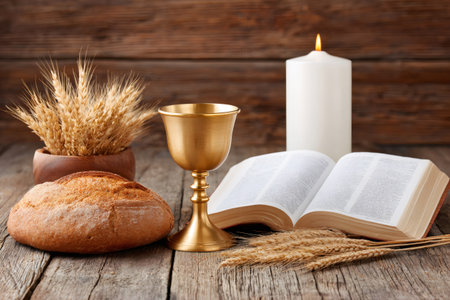 Golden chalice, bread, wheat and bible near a burning candle are representing the holy communionの素材