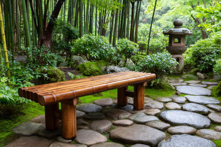 Bamboo bench rests on a stone path in a serene Japanese garden, surrounded by lush greenery and a stone lanternの素材