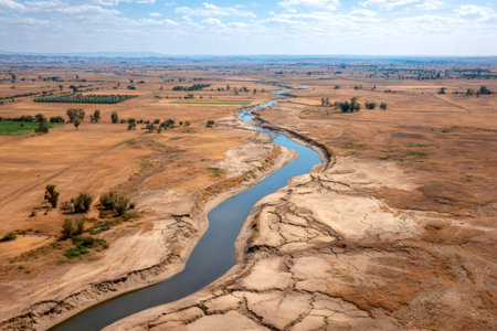 Aerial view of a river snaking through a parched landscape, highlighting the impact of drought and climate change on agriculture and ecosystemsの素材