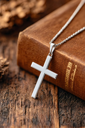Silver cross necklace on old book evokes themes of faith, tradition, and spiritualityの素材