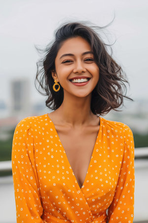 Portrait of a beautiful young woman smiling and showing her white teeth, wearing an orange dressの素材