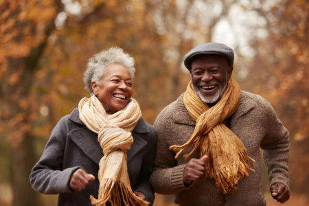 Happy senior black couple jogging for fitness and health in an autumn parkの素材